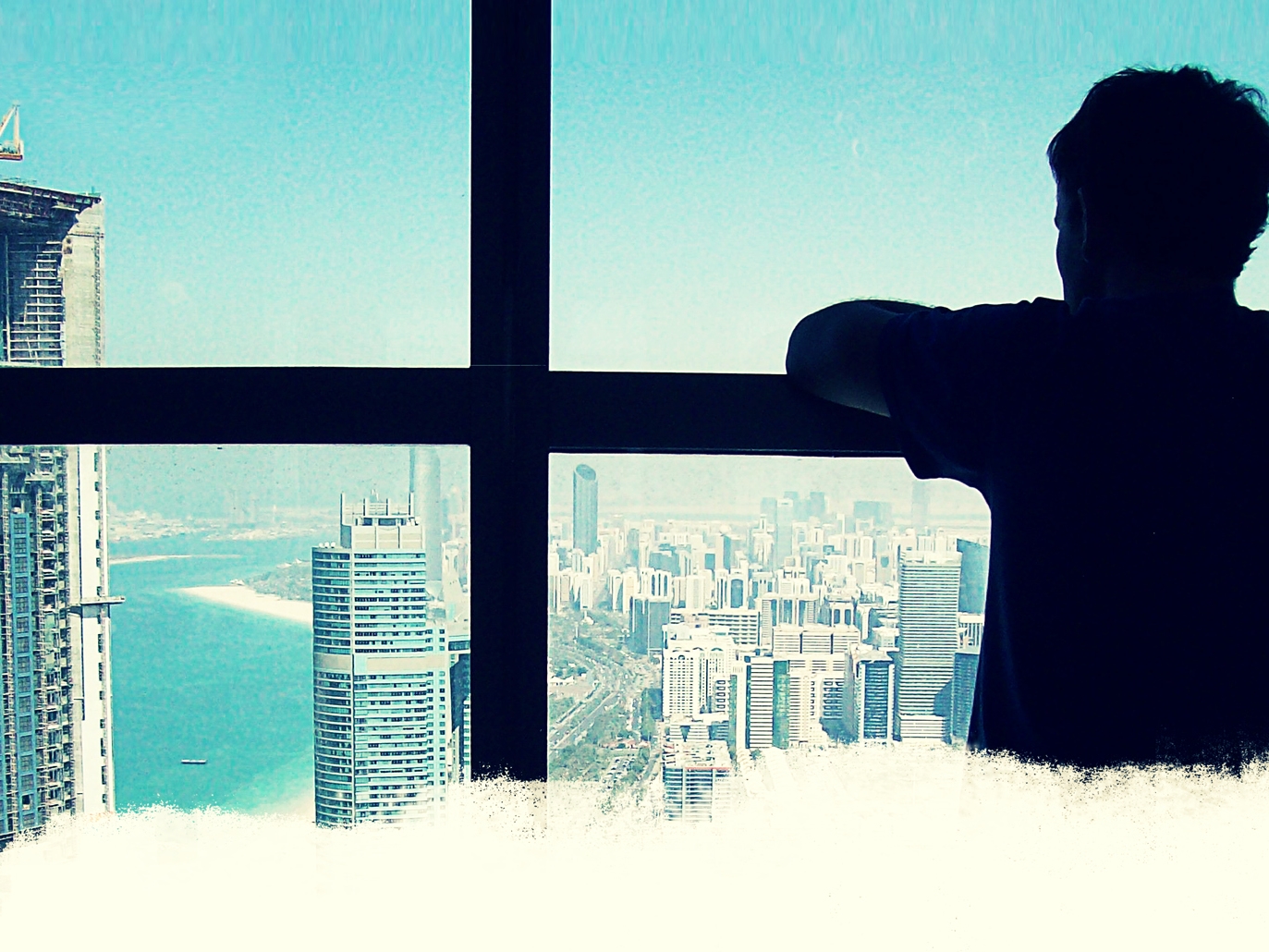 Male looks out at skyscrapers of a metropolis on a bight, cloud free day. Lead film image