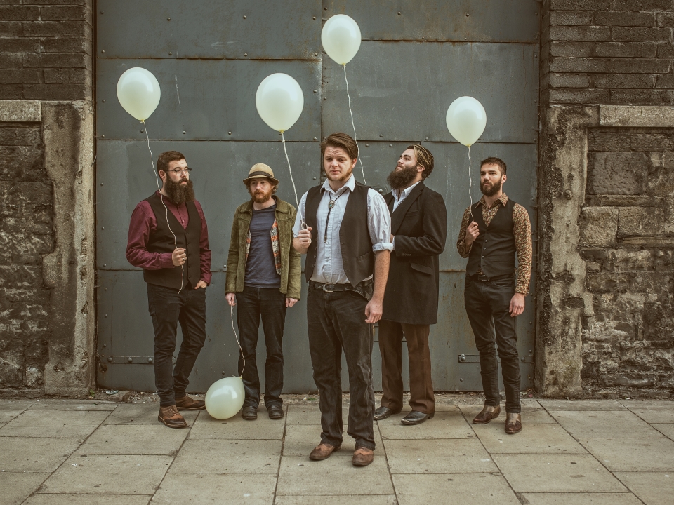 Press image of 5 of the eskies holding white ballons infront of a large industrial door