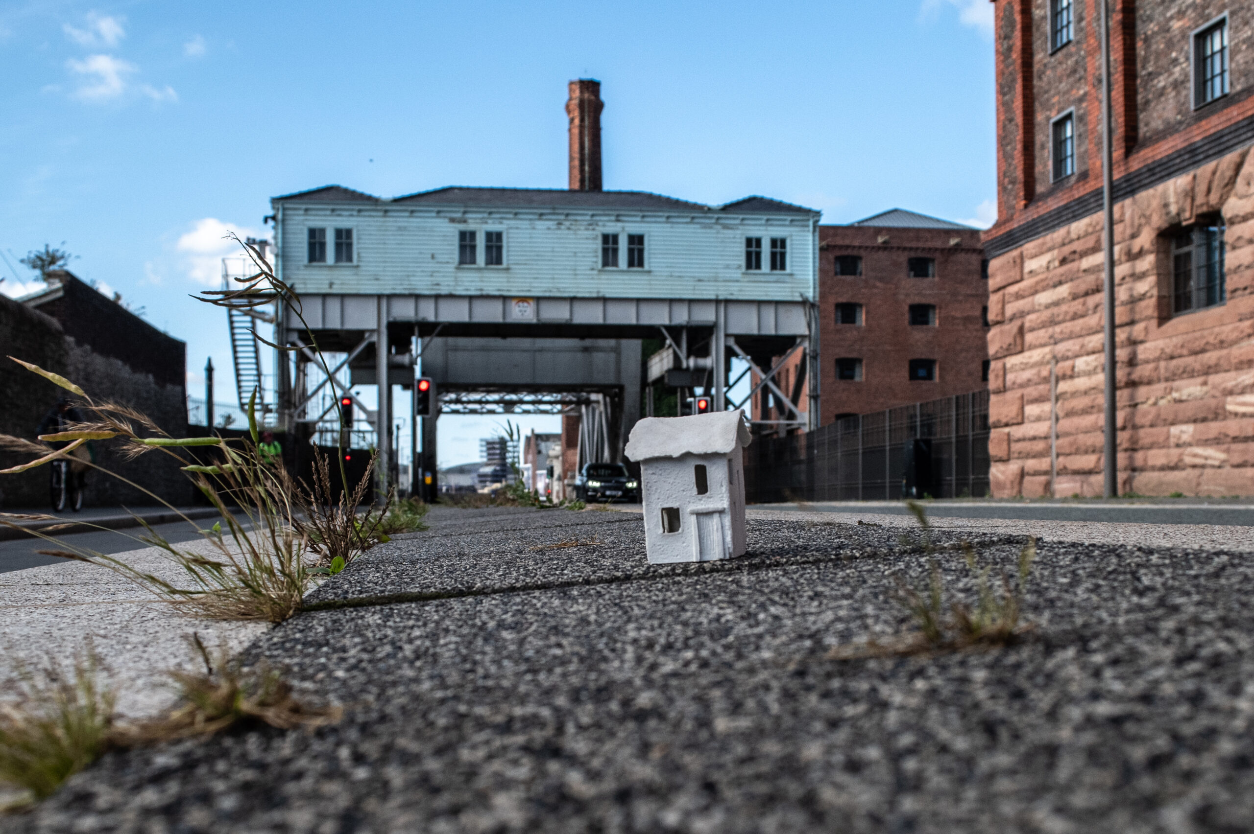 Porcelain house on pavement infront of stilted building.