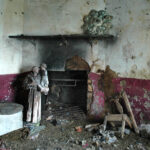 Broken furniture, a large religious statute and a fallen ceiling rose surround a broken-down hearth