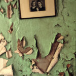 A framed photo sits on a paint peeling wall
