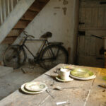 Plates on kitchen table overlook a disused bike